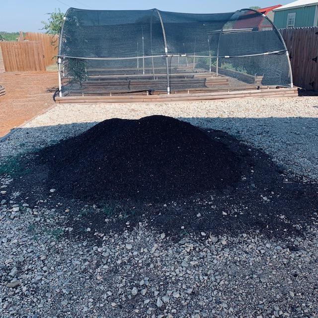 This little mound of dirt on our driveway is one yard of dirt. You can see some of our hoop houses behind it.