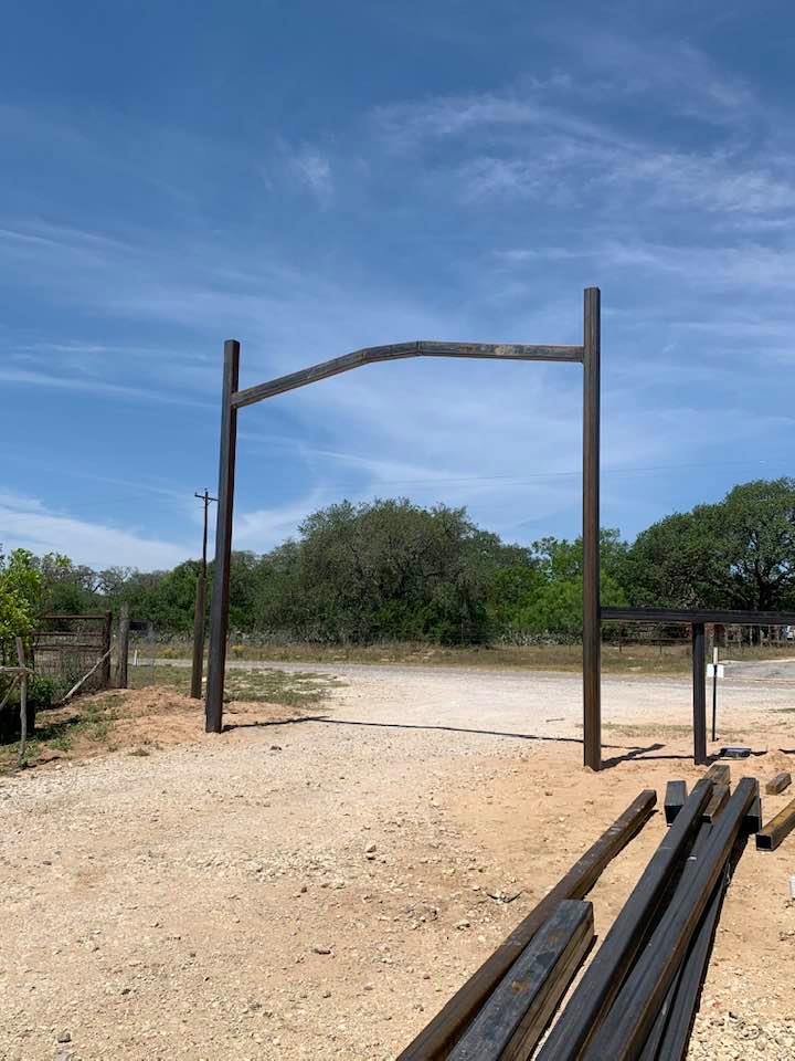 Progress is being made on our gate. The arch connecting the two tall poles was put up this morning.