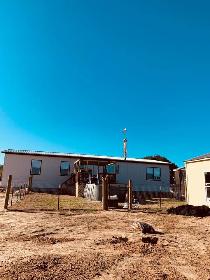 This is a view of our backyard with a  beautiful blue sky this Sunday with the Texas flag and the flag of the USA flying from the water well rig over our home.
