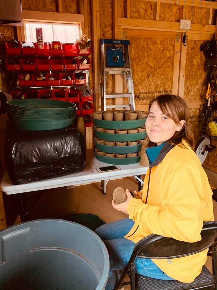 Bethany is in her new farm work area, filling CowPots with soil and then planting seeds to take to the greenhouse. She has A/C and a heater in there. The trash can has soil in it. Bethany is in her new farm work area, filling CowPots with soil and then planting seeds to take to the greenhouse. She has A/C and a heater in there. The trash can has soil in it.