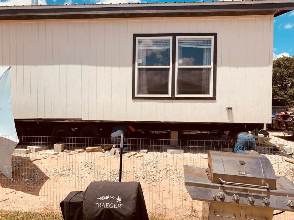 The team is taking the wheels off of the house, leveling it, and putting it on bricks.
