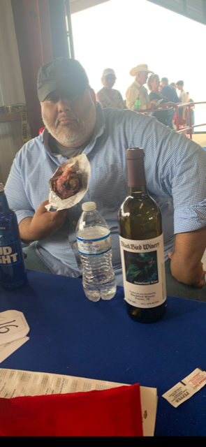 Jay with a turkey leg, his own black cap, and the bottle of red strawberry wine for us before it broke sitting in the auction area.