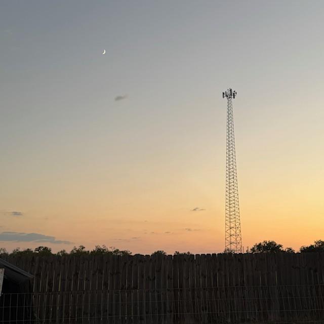 The cell tower at sunset with a crescent moon and subtle pink skies. The cell tower at sunset with a crescent moon and subtle pink skies.