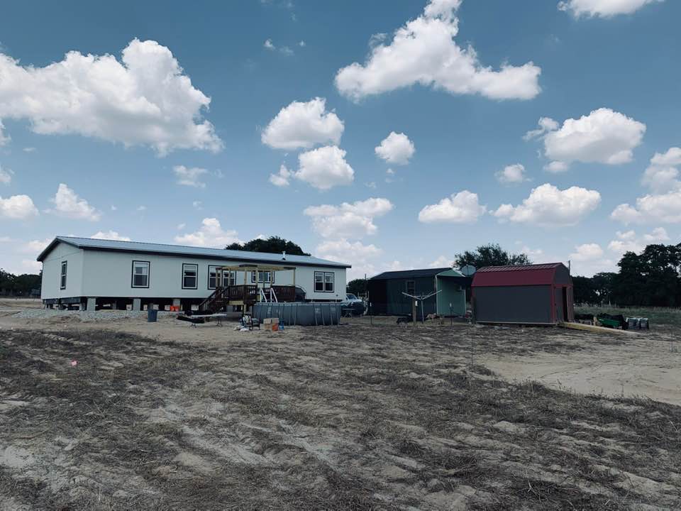 This is our Farm from behind the house and sheds. We are living in  the green shed, waiting for our home to be ready and for utilities. It is hot!