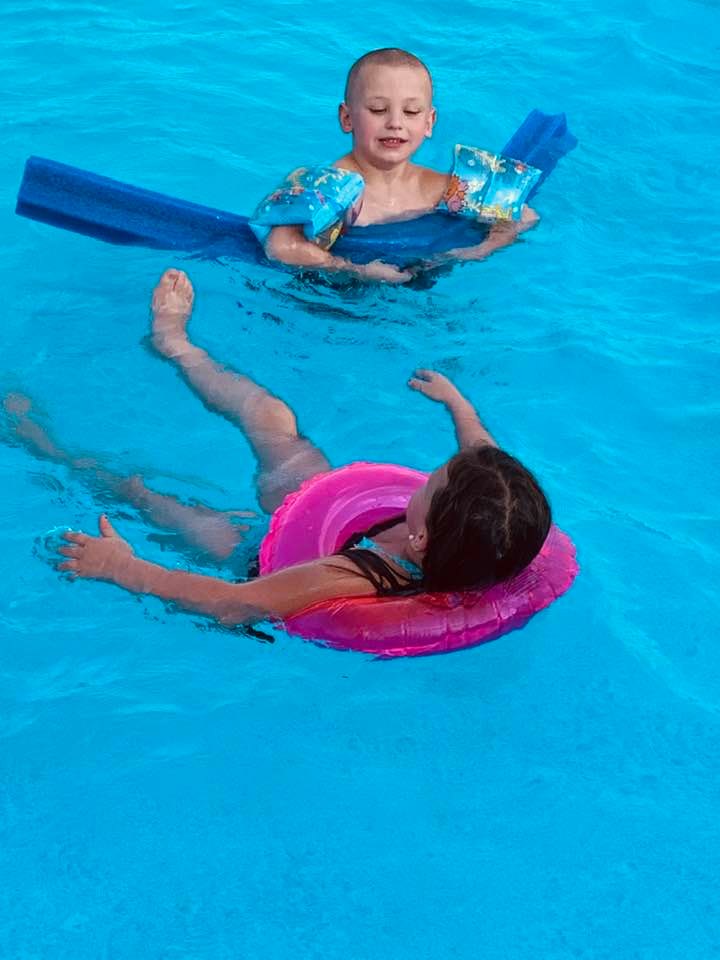 Max and Holley are floating in the pool while their dad is stuck up on the hill.