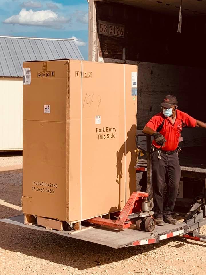 Here the driver is bringing the fridge off of the semi with the lift on the back of the truck.