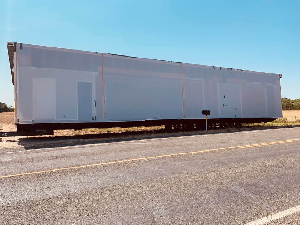 The front half of our new home dropped off on the side of the road near our property. You can see our brand new mailbox in front of the neighbor's property.