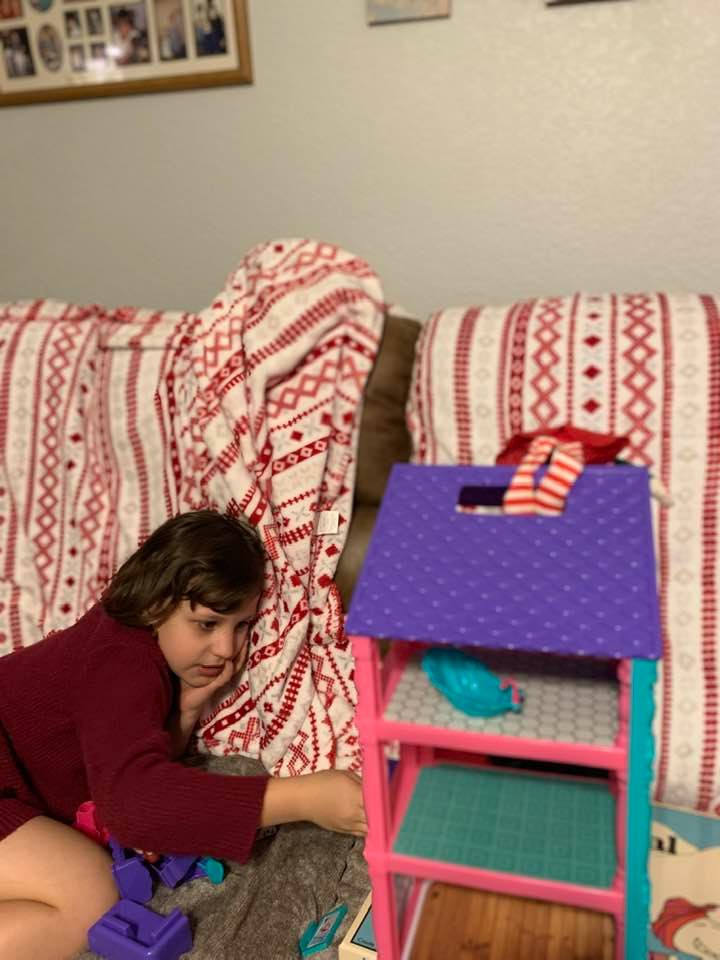 Holley is on our new couch with Christmas blankets and a new dollhouse.