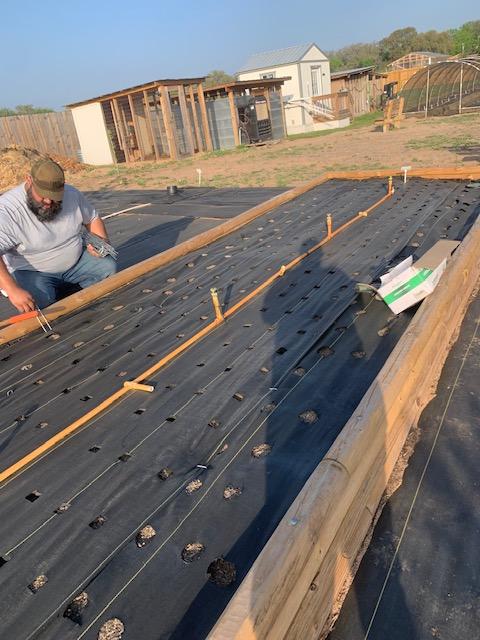 John is pinning down some of the weed barrier that had come up out in the back 40. It is very windy today.