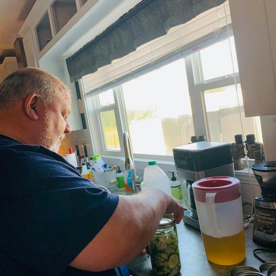 David is adding liquid to the pickles he put in the jars.