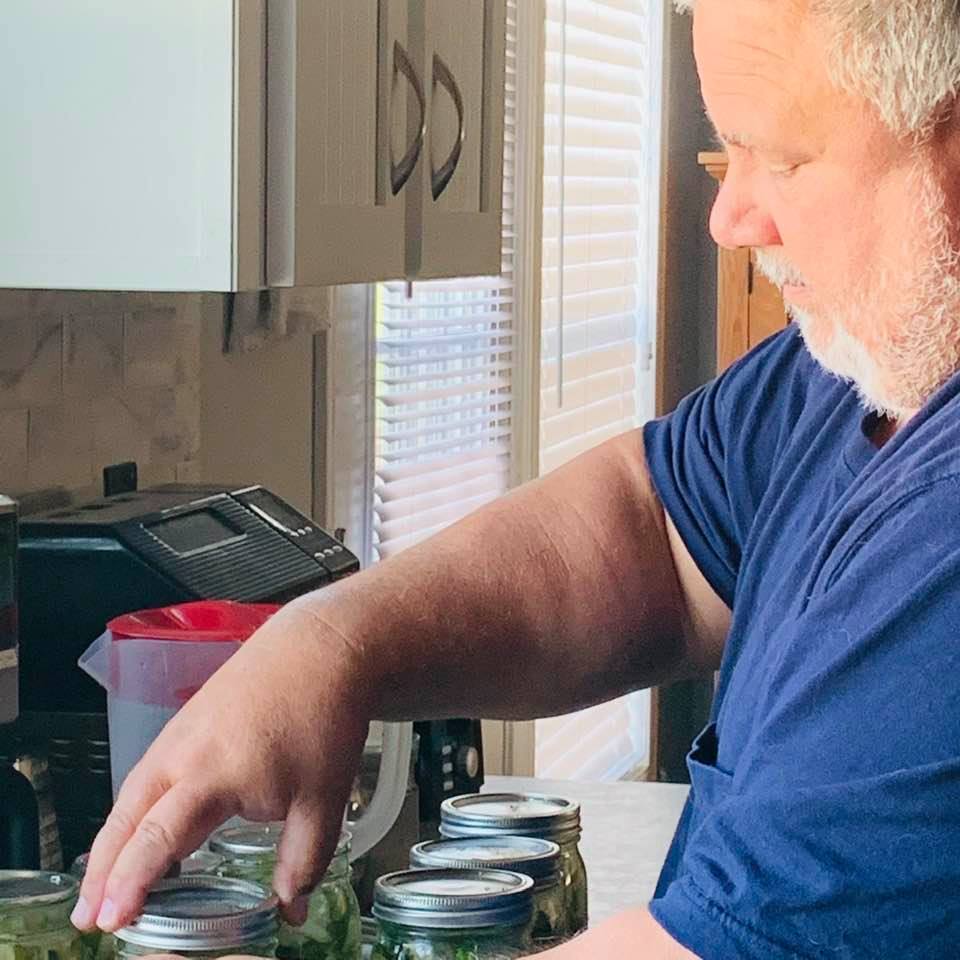 Now he is putting the lids on before putting the jars in boiling water.