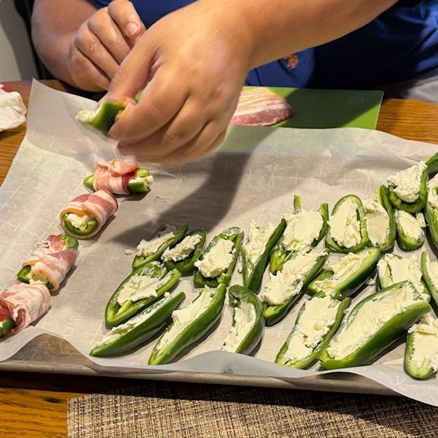 David cut the jalapenos up, took out the seeds, stuffed them with cream cheese, and wrapped them in bacon.