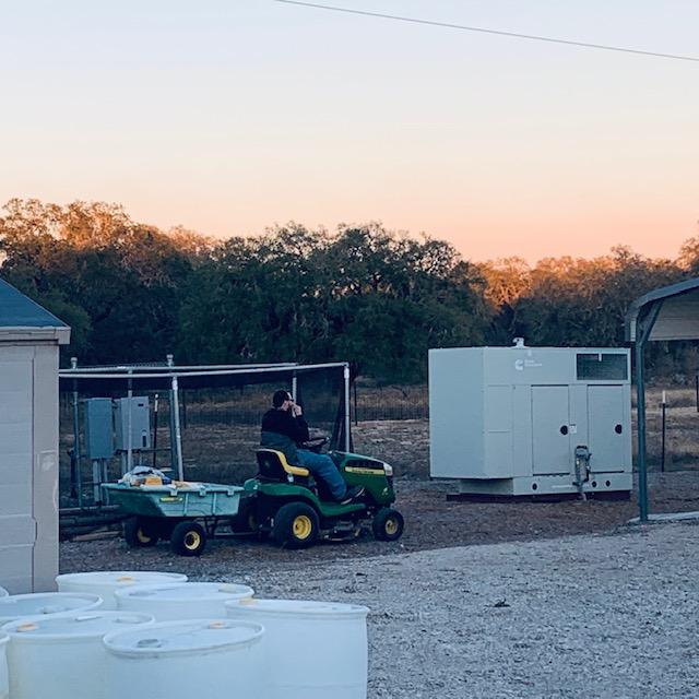 Matt taking the animal feed out back. There is our generator to the right. It still comes on every Thursday as a test. If we lose electricity, it will take care of that.
