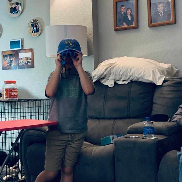 Max is trying out his new binoculars in the den.