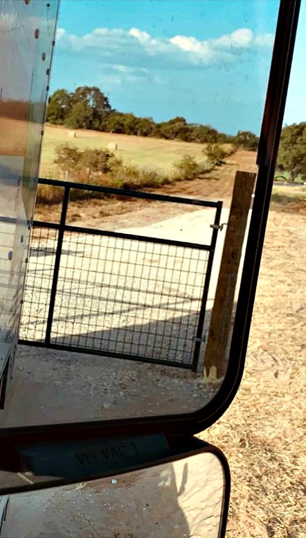Our front gate is seen through the U-Haul mirror as we are leaving the property.