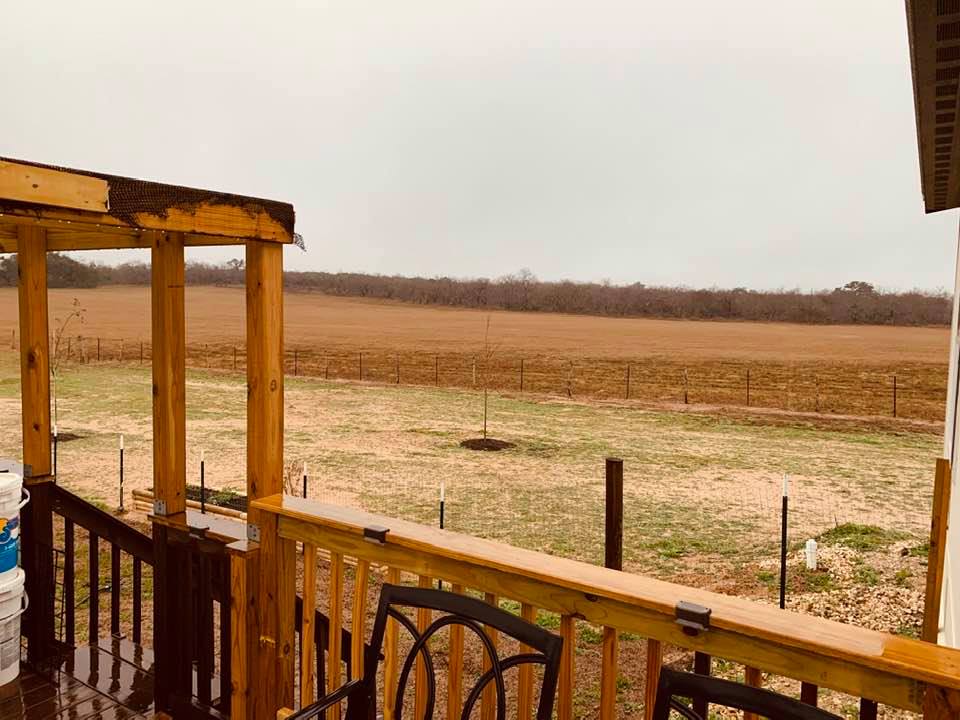 A view from the back porch. You can see it is raining. Also, you can see the new raised garden bed just outside of the backyard farm fence.