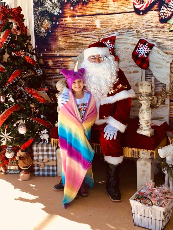 Holley visiting Santa in her unicorn blanket.
