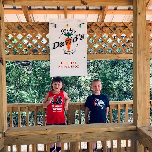 Holley and Max in front of the selfie spot in the David's Garden Seeds® gazebo. They should be out planting zinnias but don't they look cute?