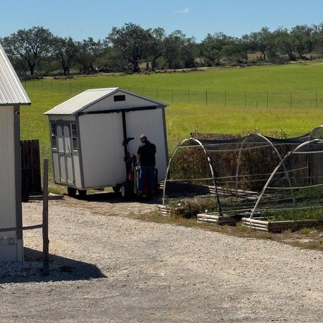 Wheels are attached and the man hooks it to a little vehicle that pulls the shed.