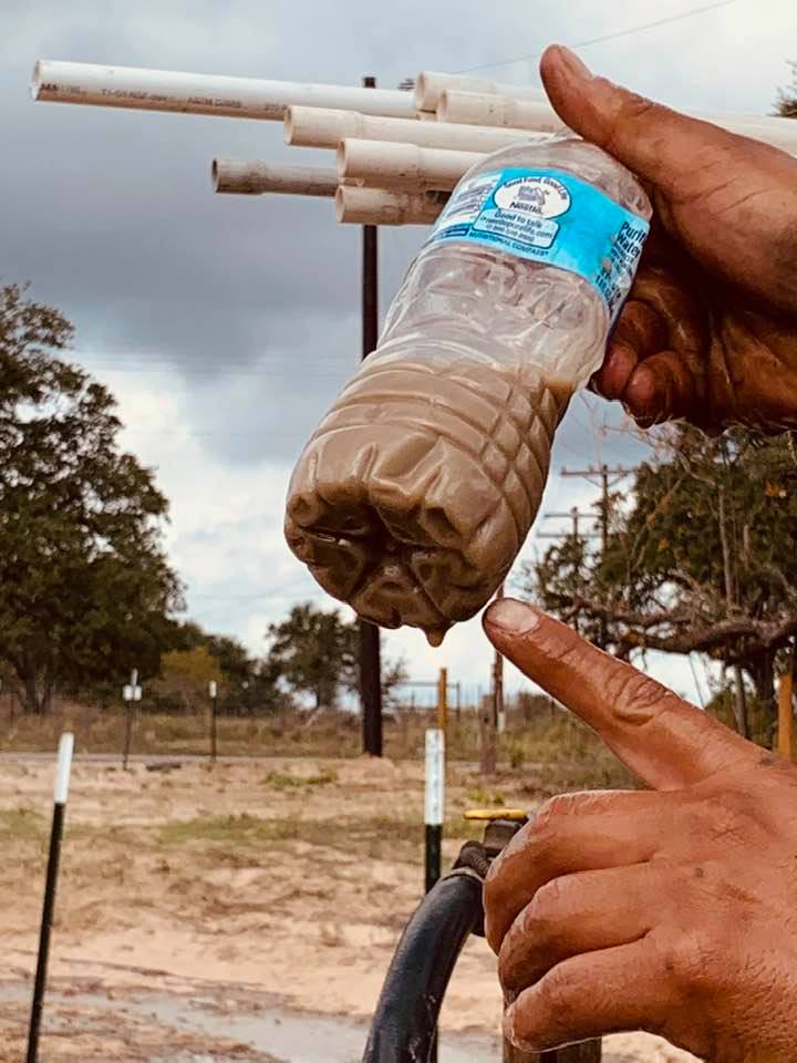 The water well is just full of sand right now. The employee shows us the sandy water he collected coming out.